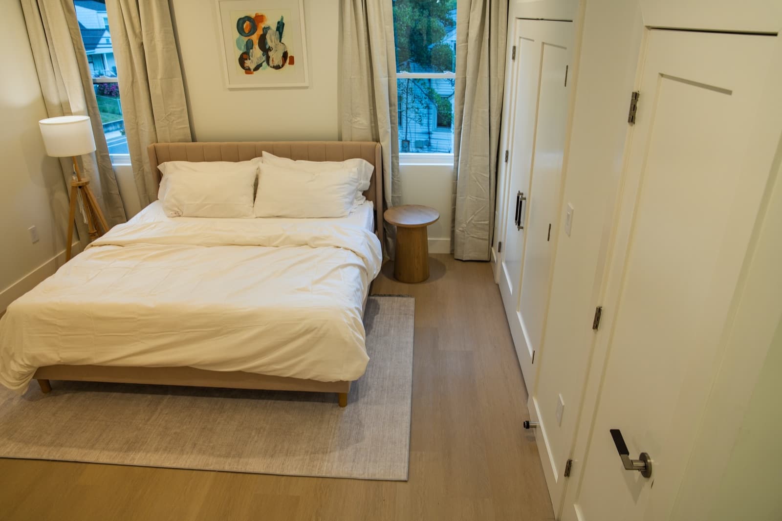 Bedroom with channel-tufted headboard, crisp white linens, and linen drapery