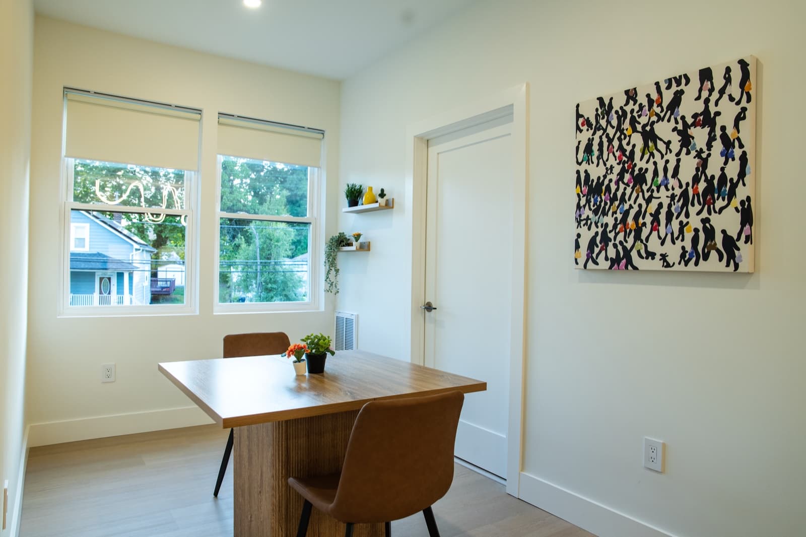 Dining nook with fresh flowers, the silhouette art piece, and a daylit window overlooking the neighborhood