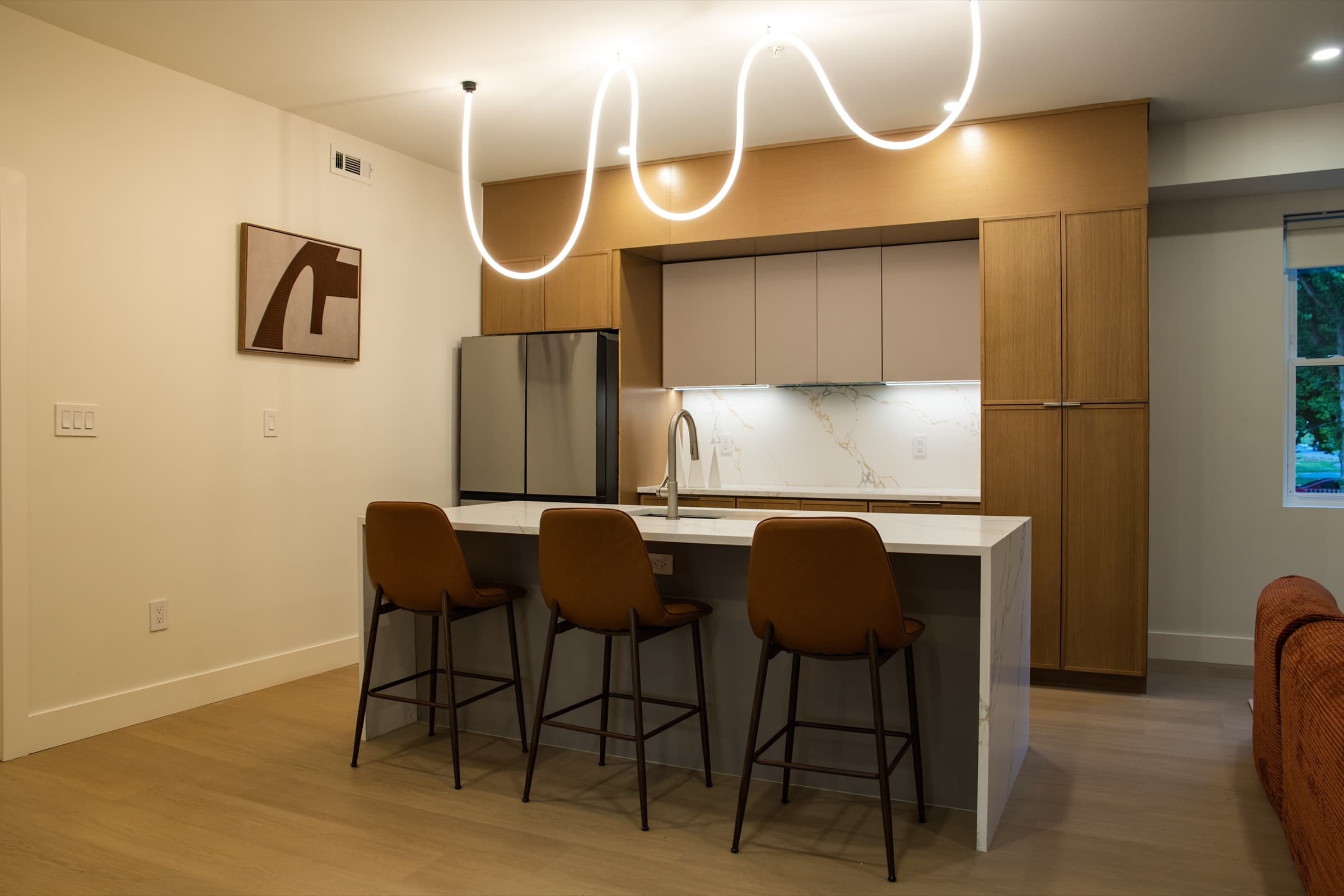 The Veyrai at Shadyside · open kitchen with marble waterfall island, wood cabinets, and warm pendant lighting